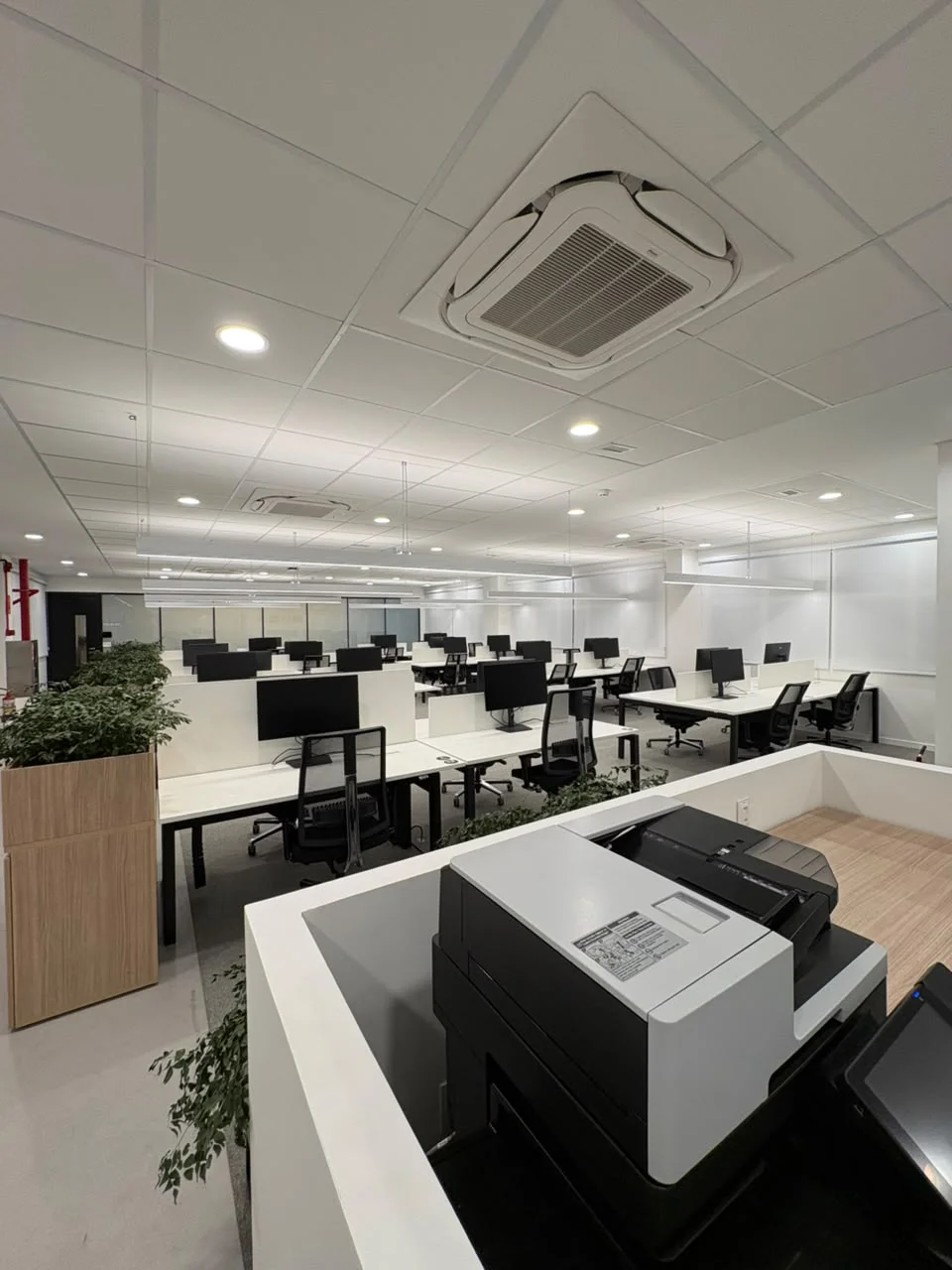 Ambiente corporativo com estações de trabalho e unidades cassete no teto